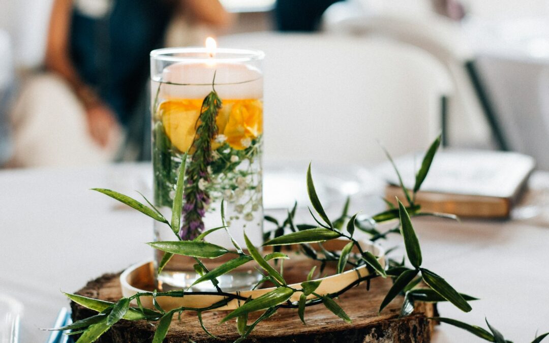 clear glass cup filled with yellow, green, and white leaves and water on brown wooden platform