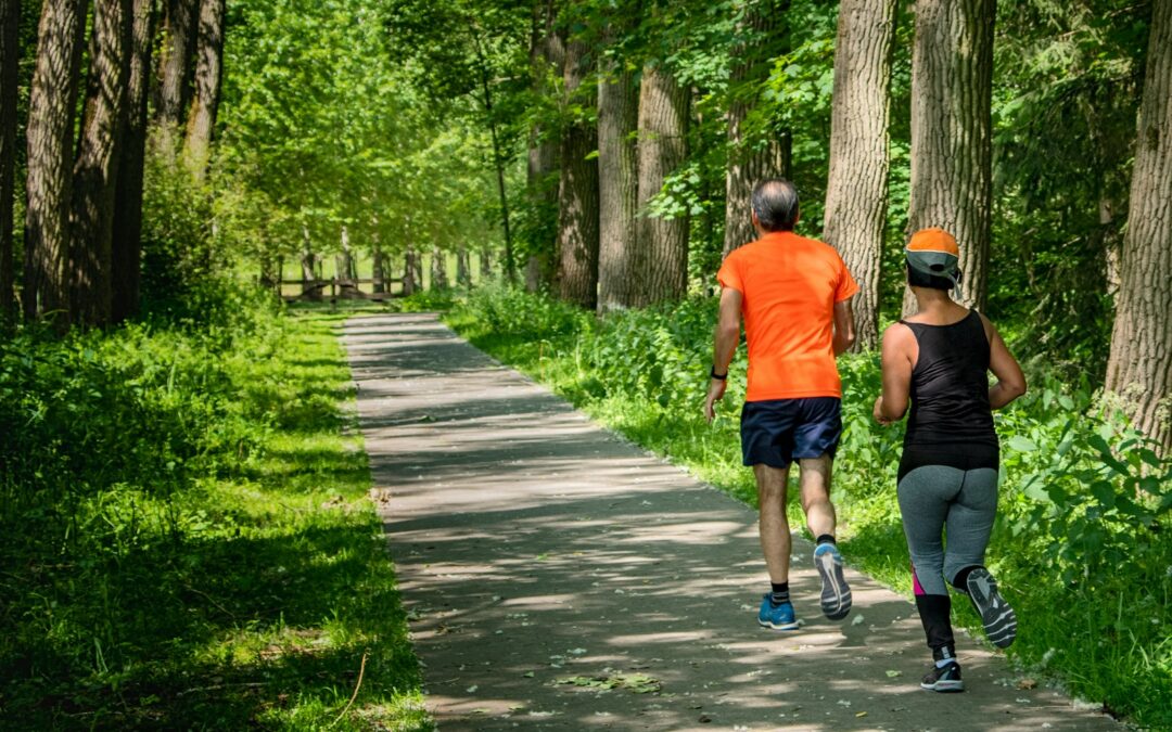 man in orange t-shirt and gray pants with blue shoes walking on pathway
