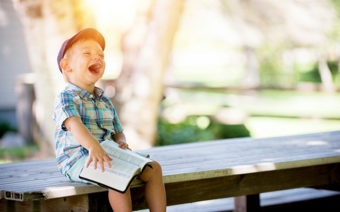 boy sitting on bench while holding a book