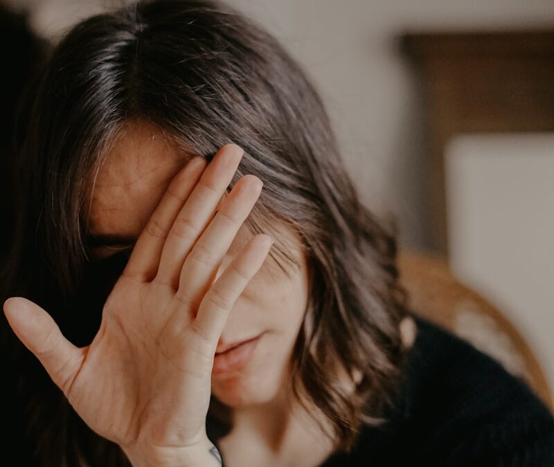 woman in black blazer covering her face
