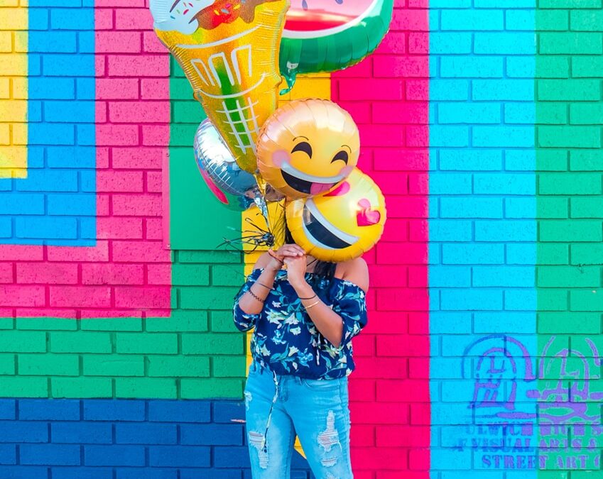 woman covering face with assorted ballons