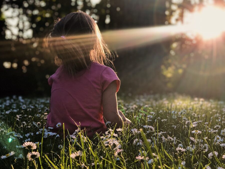 girl sitting on daisy flowerbed in forest