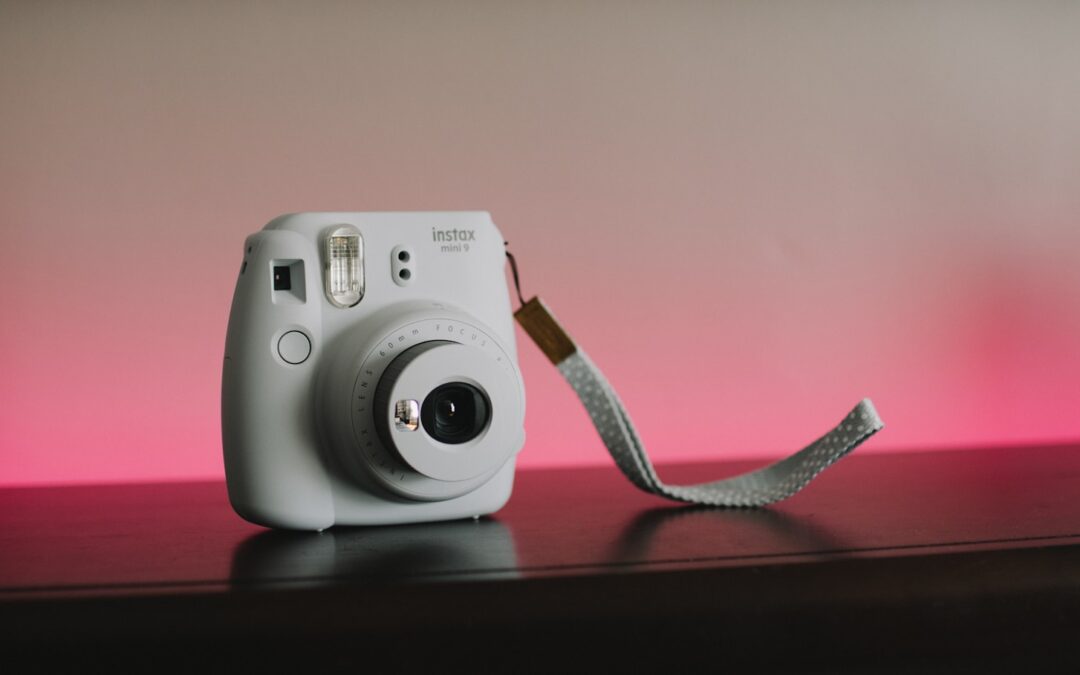 white Fujifilm Instax camera on brown wooden surface