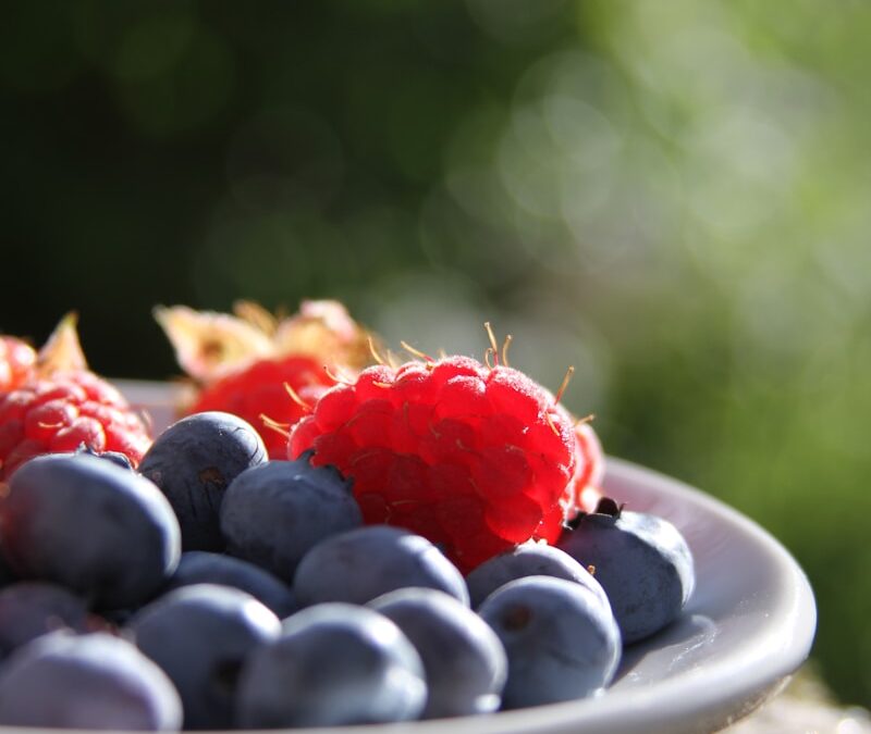 selective focus of blueberries and raspberries on bowl